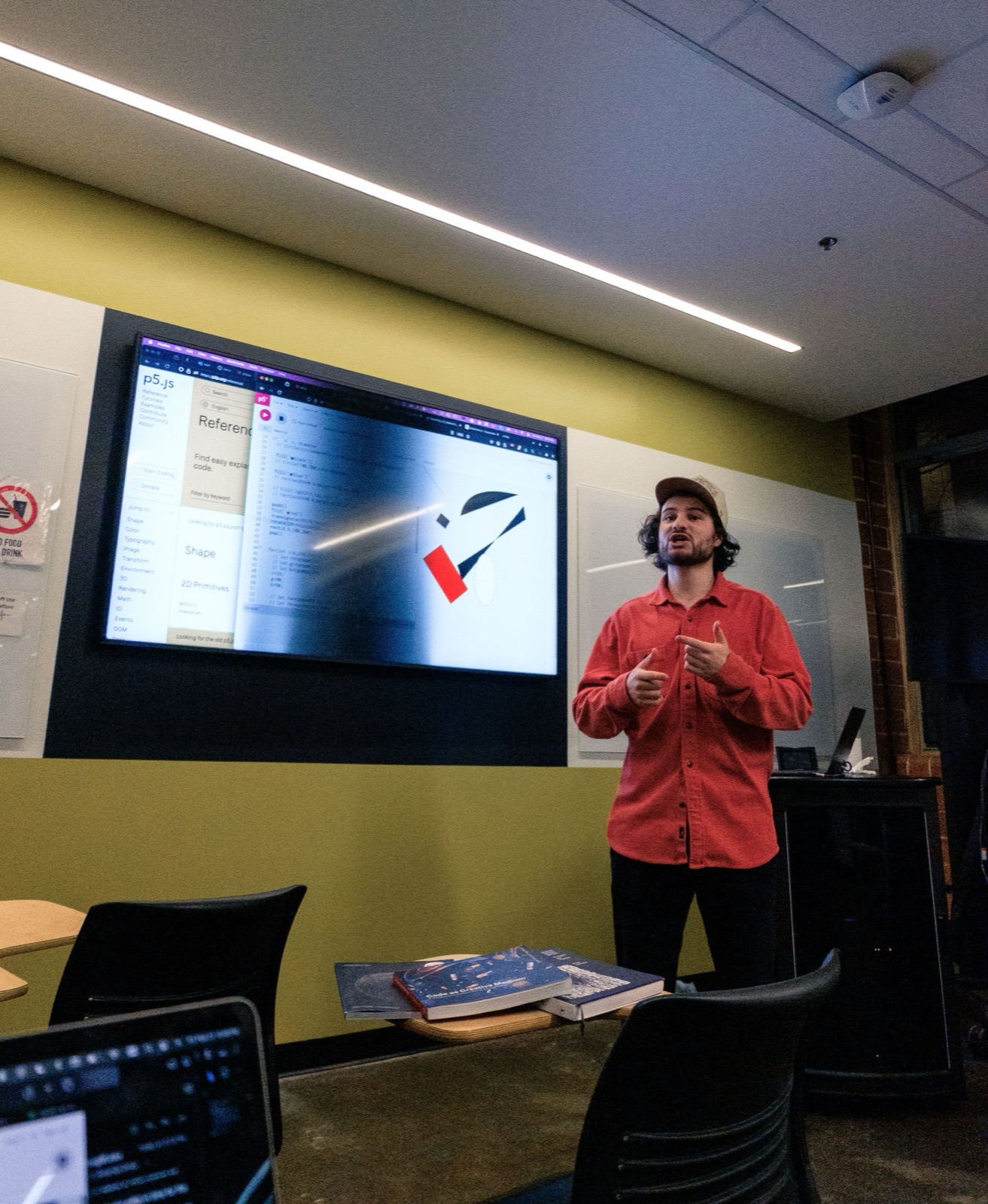 David Holcer speaks to the room, the p5.js reference and his sketch projected behind him