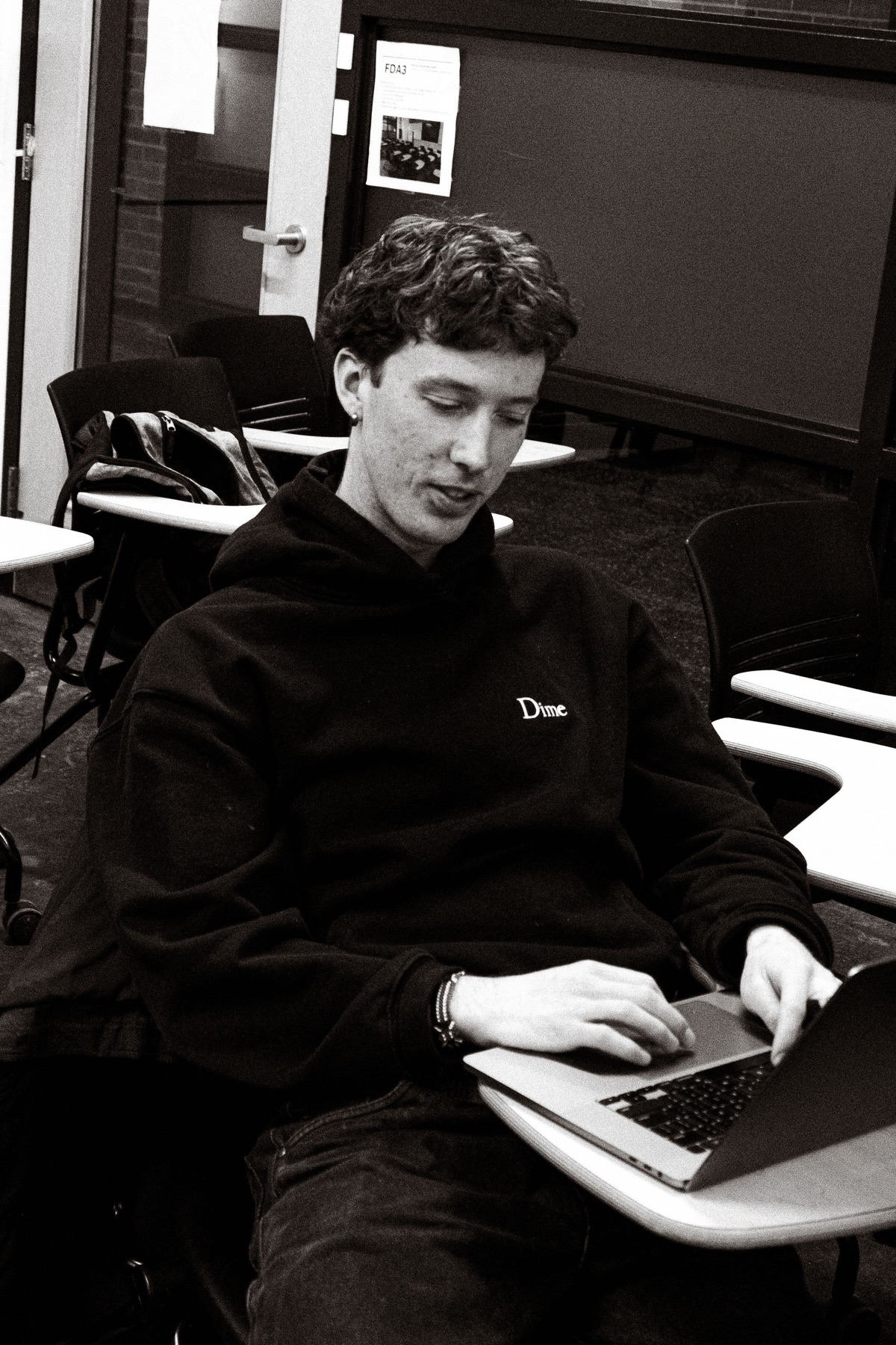 A participant smiles while typing on a laptop, in black and white