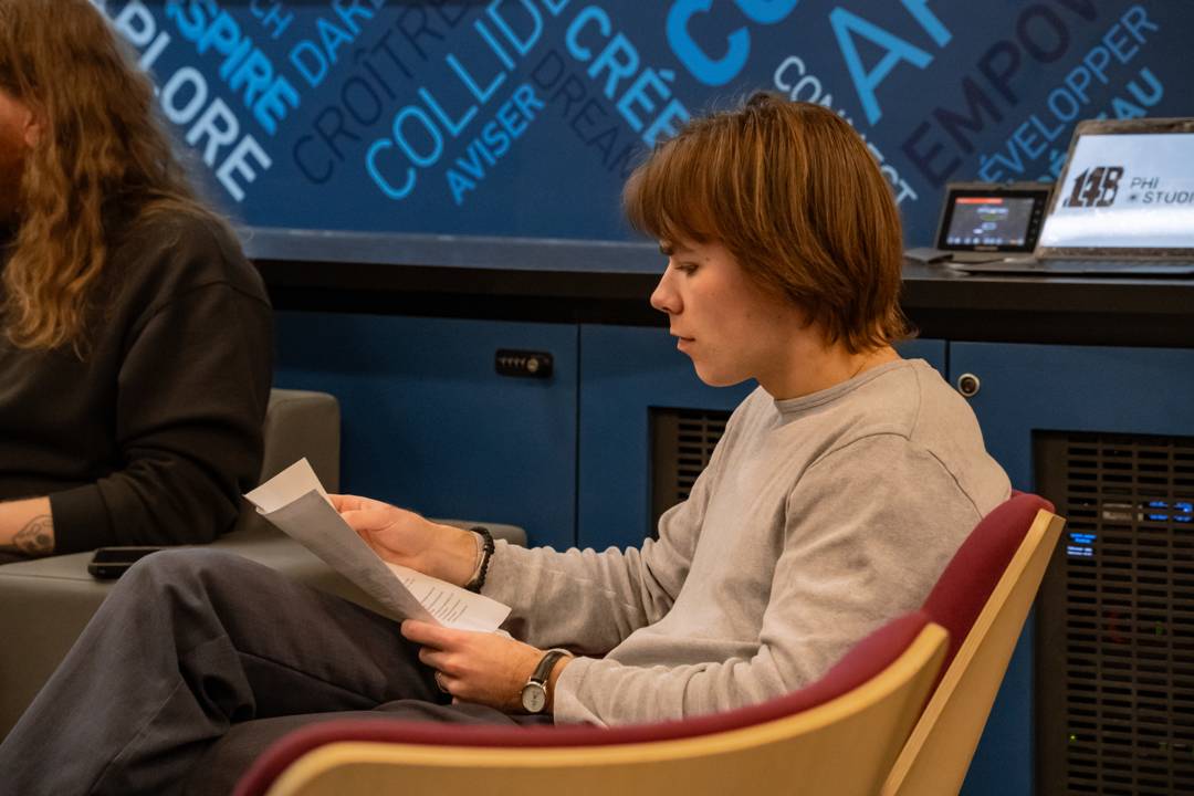 An attendee reads printed notes before the panel begins